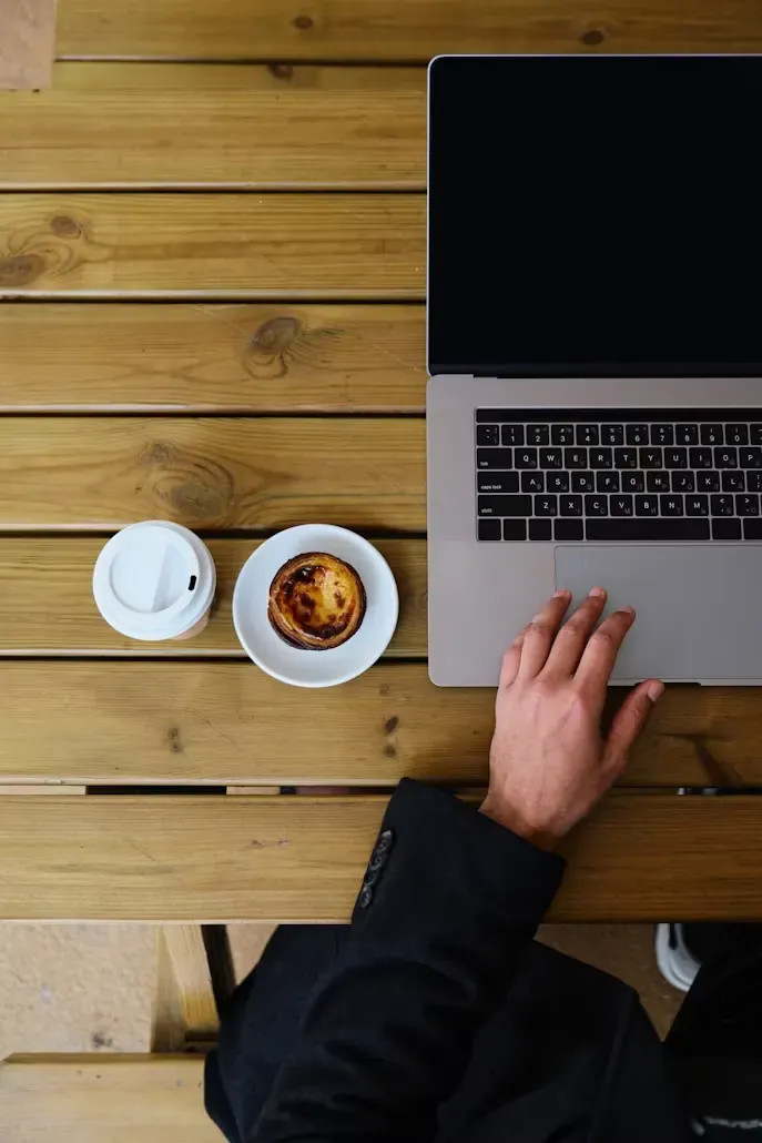 Top-down view of a laptop and coffee on a wooden table